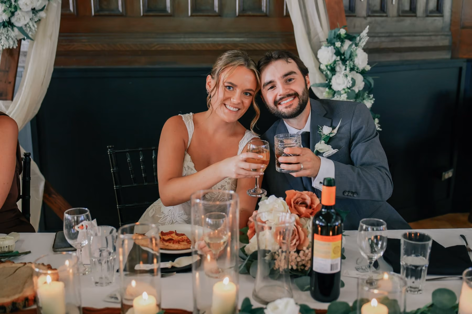 Bride and groom raise their glasses at the head table among candles.